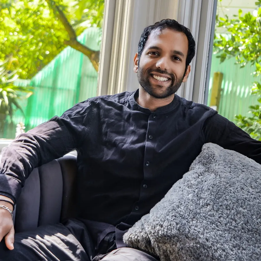 Smiling man in a black shirt relaxing on a couch