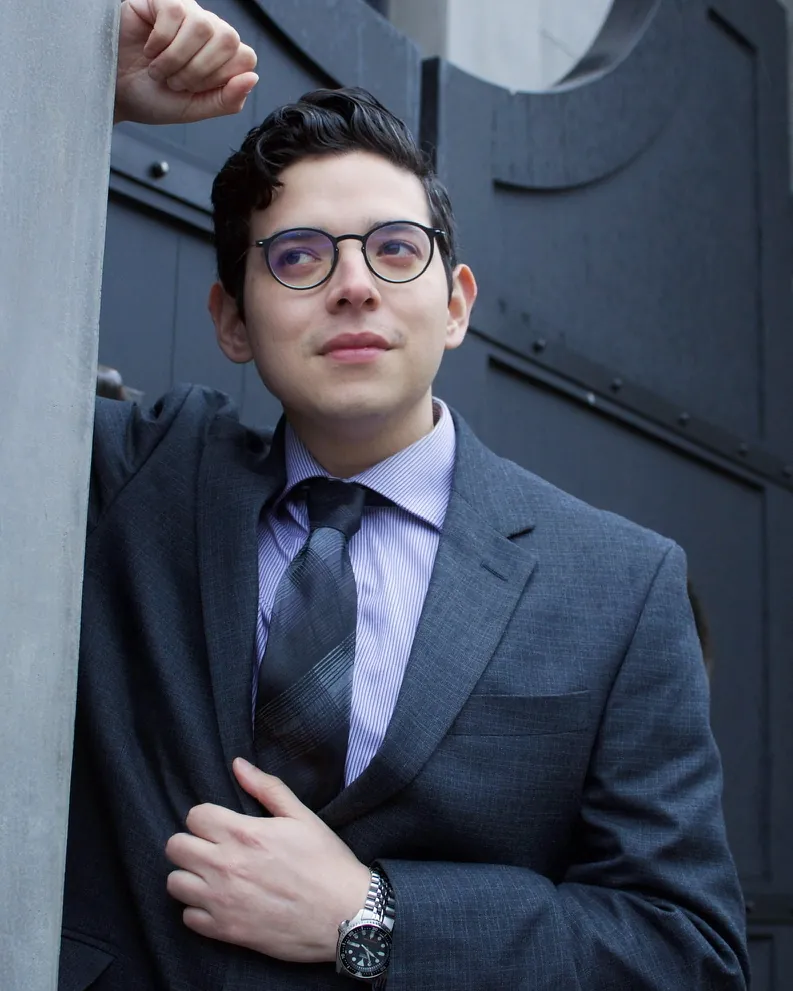 The same client after his shoot, in a grey suit and glasses, looking confident