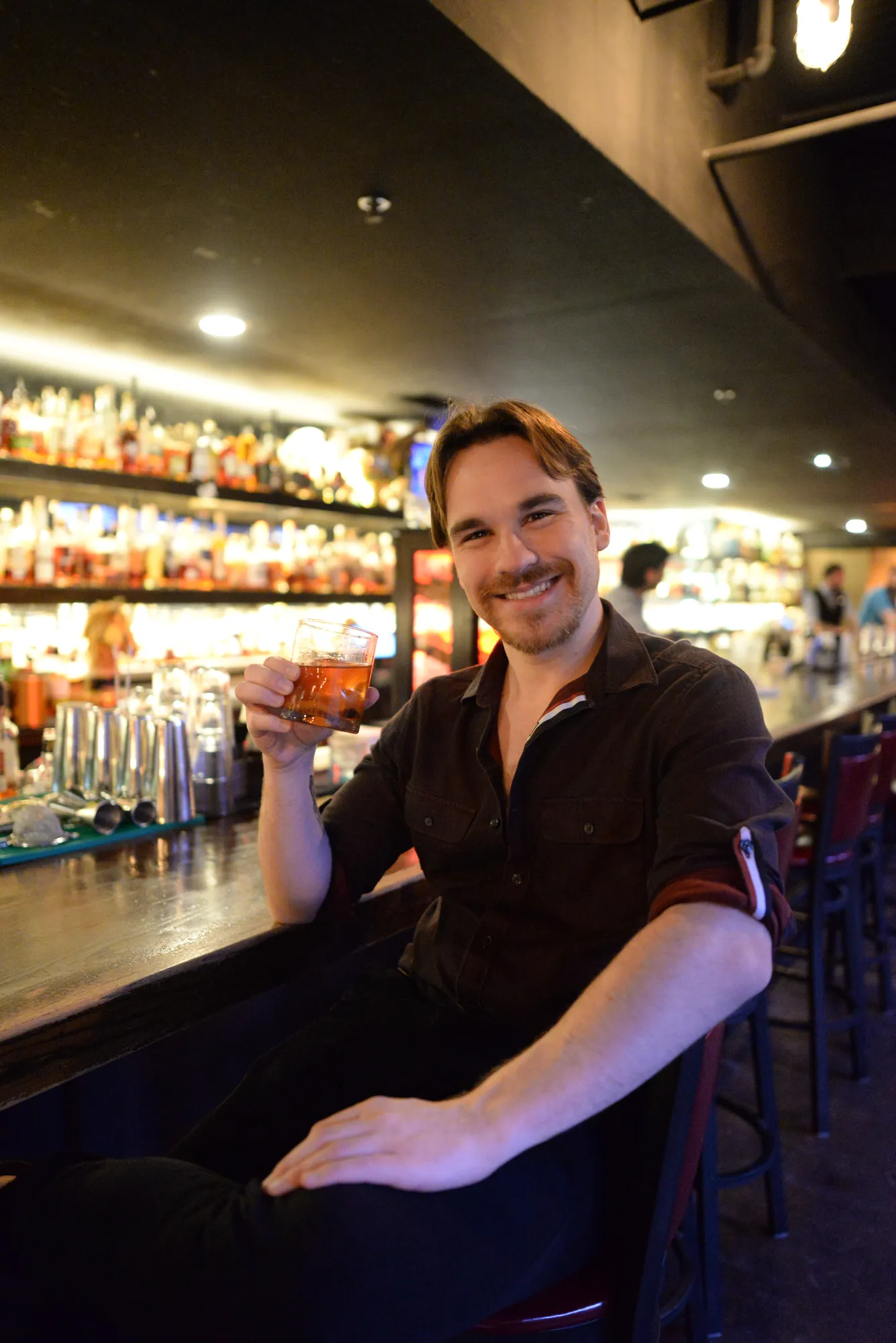 Man smiling at a bar holding a drink