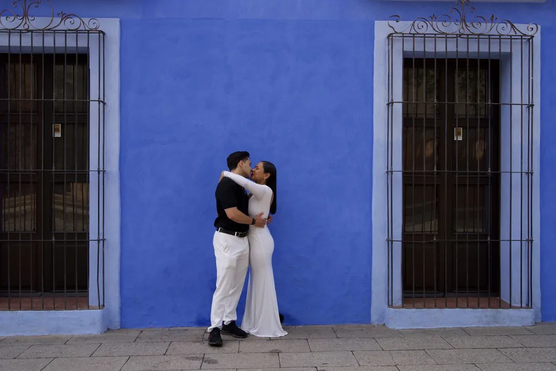 Couple embracing in front of a bright blue wall