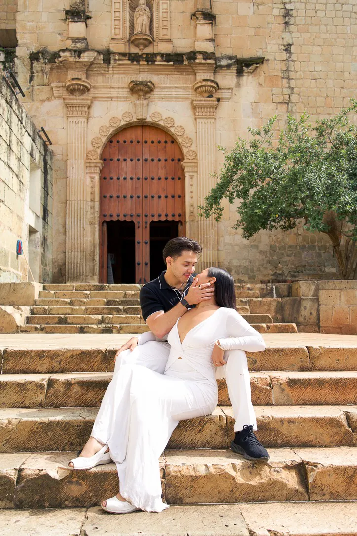 Couple dressed in white sitting on old stone church steps