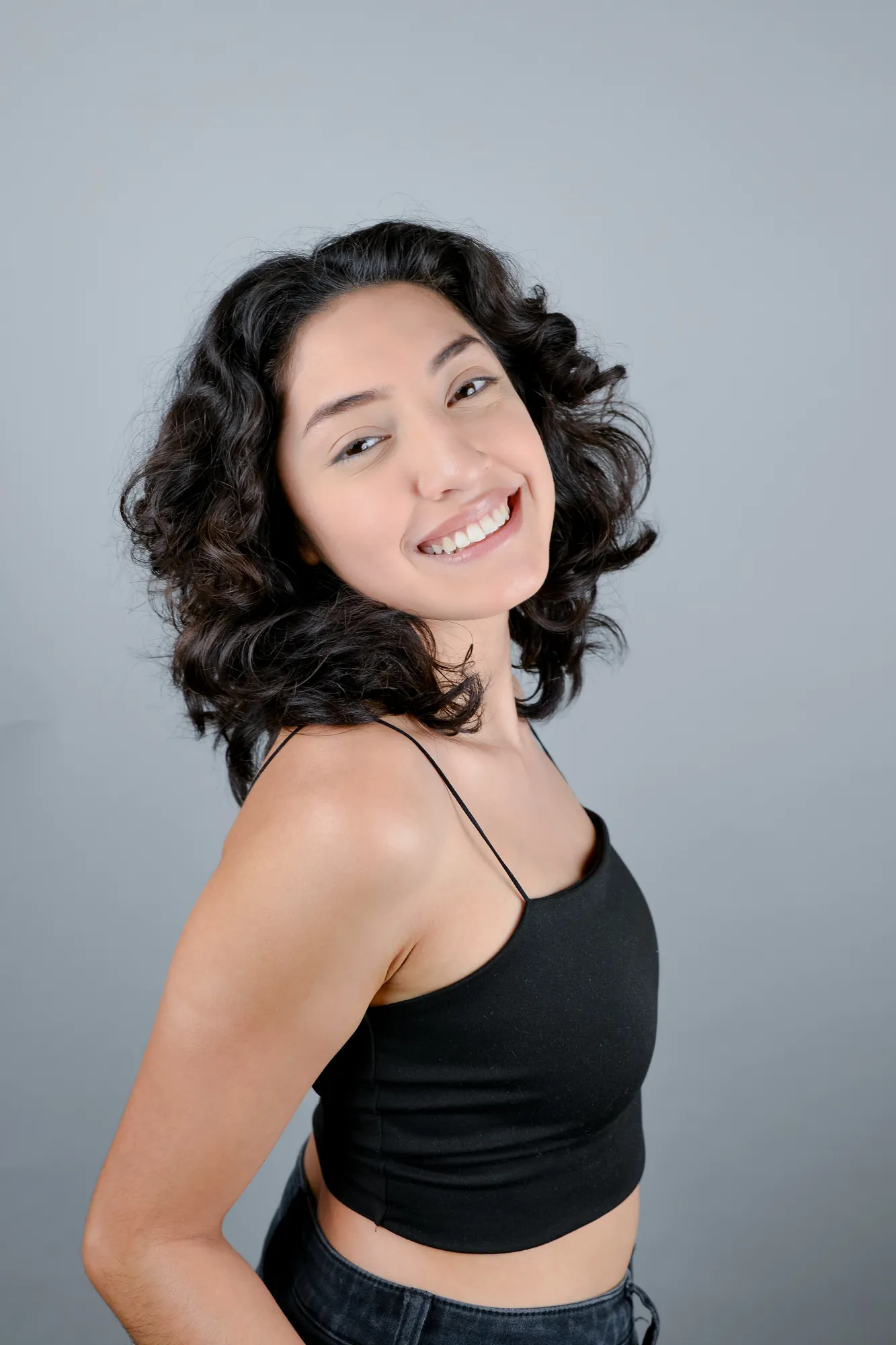 Smiling woman with curly hair against a grey backdrop
