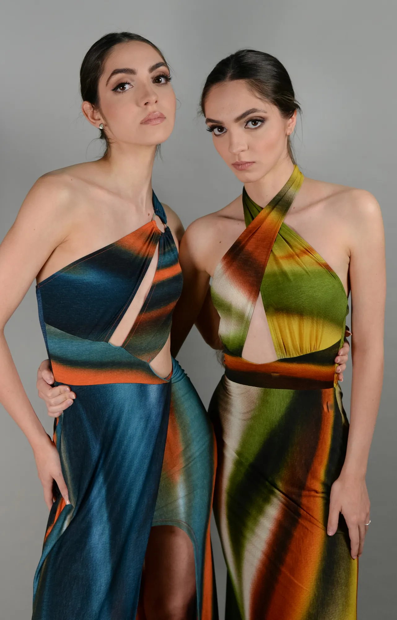 Two people in flowing printed dresses, photographed in studio light